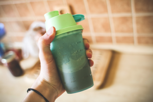 handstand push-up performance supplements post-workout products man holding green protein shake